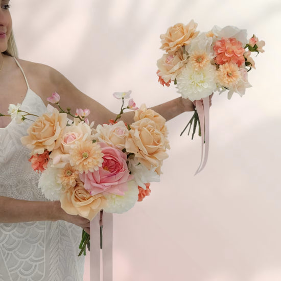 Two hands holding two peach and white wedding bouquets