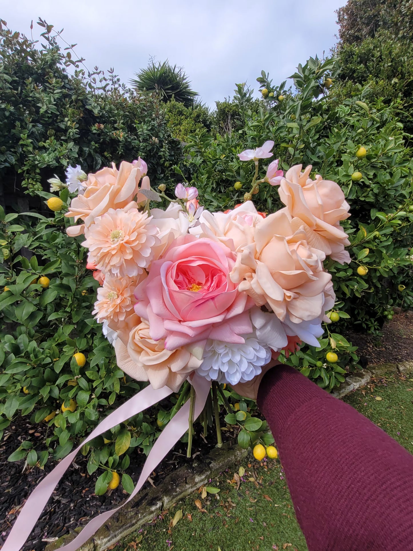 Bridal bouquet held by a person against a green garden background