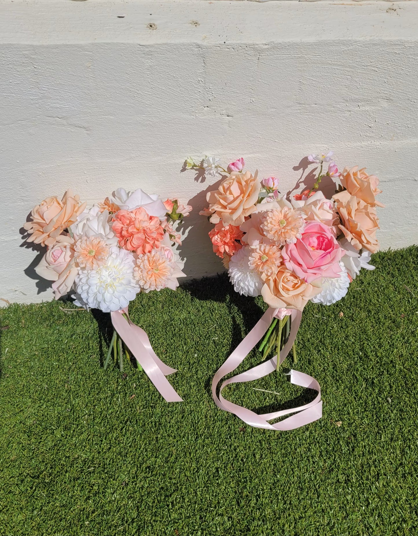 Two wedding bouquets on a grassy surface with a light wooden background