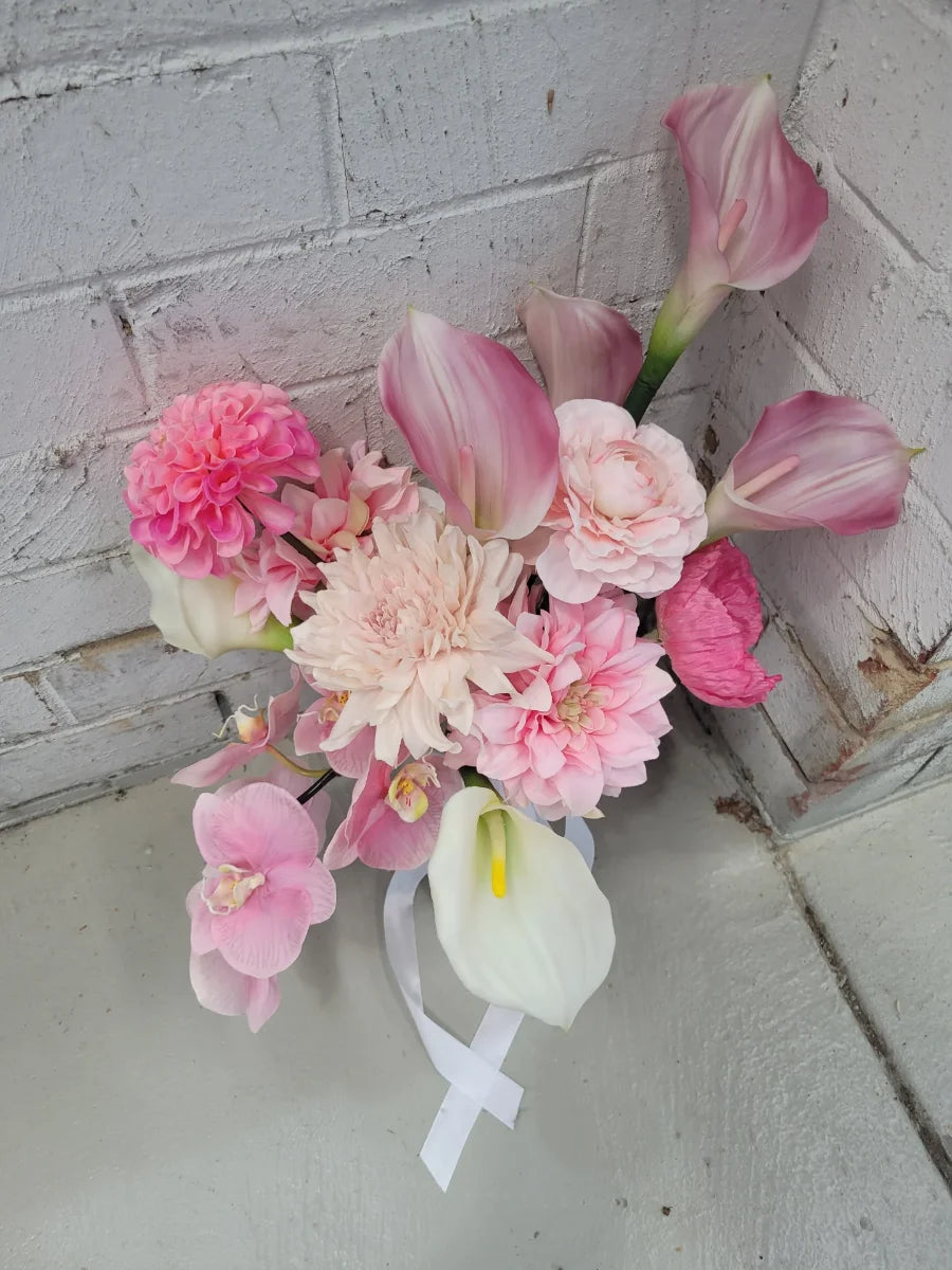 Bouquet of pink and white flowers against a light gray brick wall.