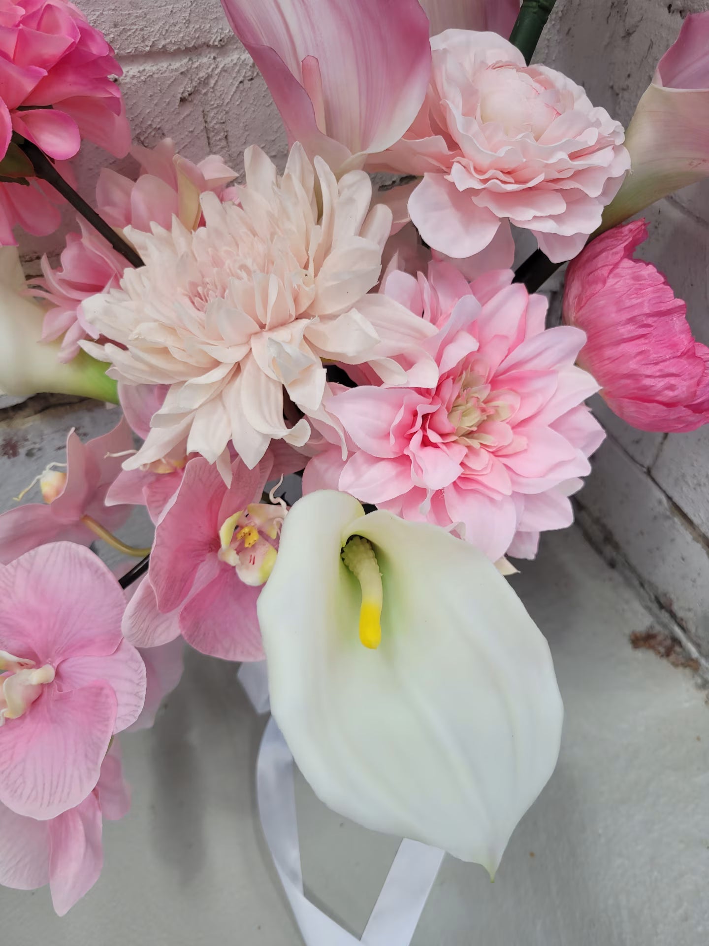Wedding bouquet of pink and white calla lilly on a textured surface