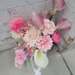 Wedding bouquet of pink and white flowers against a textured wall.