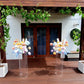 Decorative flowers on clear stands in front of a building with wooden deck and greenery.