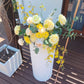 White plinth with a large yellow flower arrangement on a wooden deck