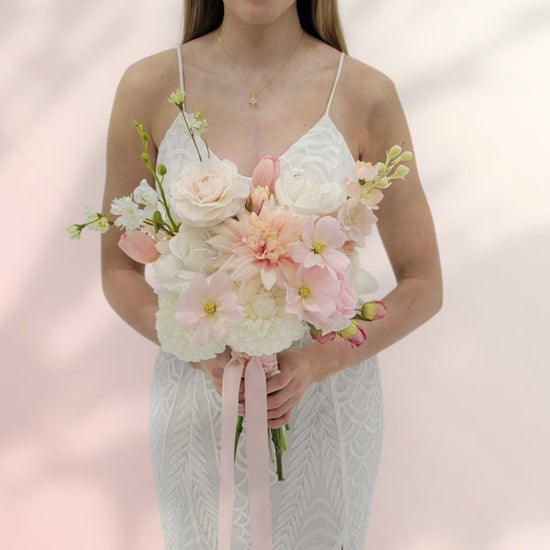 Lady holding a bridal bouquet that is soft pink and white