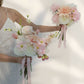 Two wedding bouquets of pink and white flowers held by a person in a white dress against a light background.