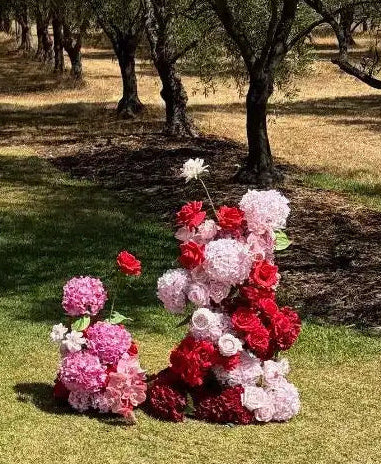 Floral arrangements in a garden setting with trees and grass.