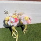 Two floral bouquets with yellow ribbons on a grassy surface against a white wall.