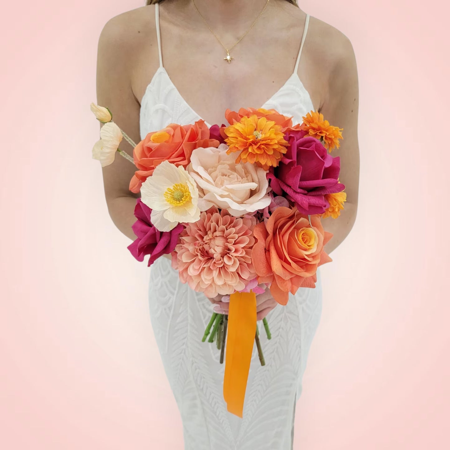 Woman holding a vibrant wedding bouquet of flowers against a pink background