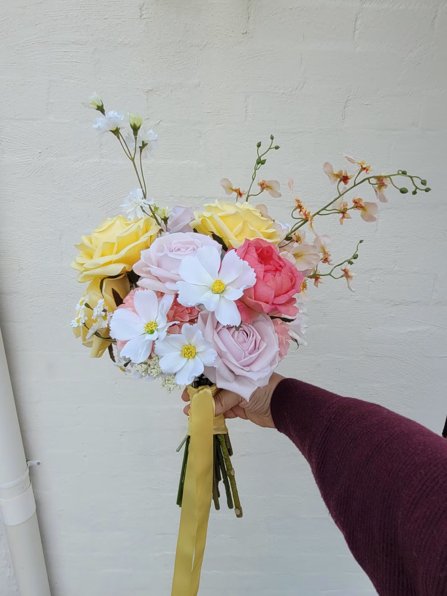 Bouquet of flowers held by a person against a plain background