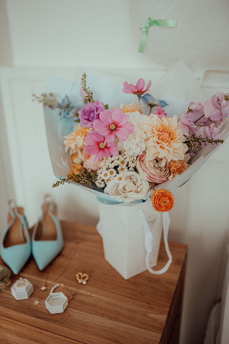 Pastel bouquet of flowers beside female wedding accessories