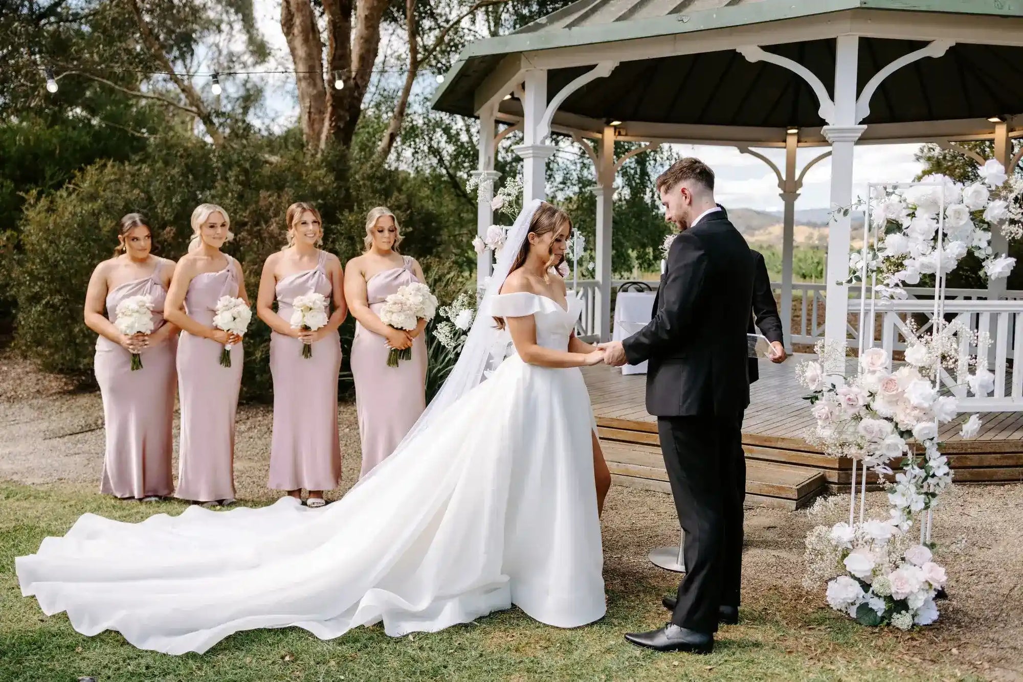 wedding ceremony with bride and groom in front of floral towers and a pegola