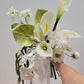 Bouquet of white flowers held by a hand against a plain background